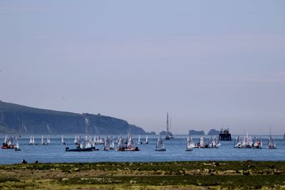 Sailboats moored on sea against sky