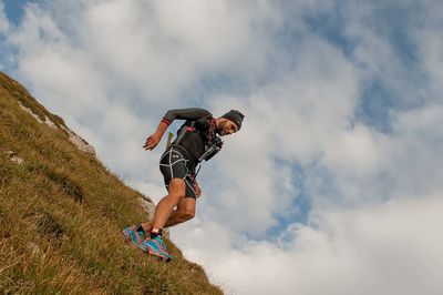 Low angle view of man jumping against sky