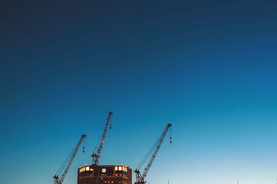 Low angle view of crane against clear blue sky