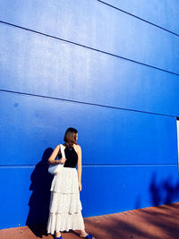 Rear view of woman standing against blue sky
