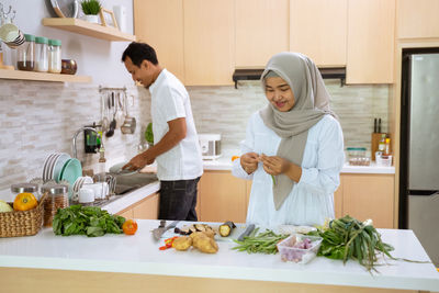 Woman standing by food in kitchen at home