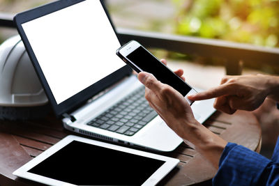 Midsection of man using mobile phone on table