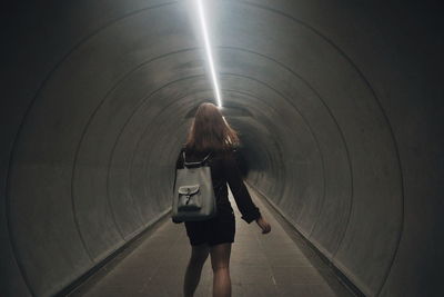 Rear view of woman standing in tunnel