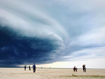 People at beach against cloudy sky