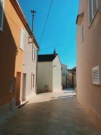 Empty alley amidst buildings in city against sky