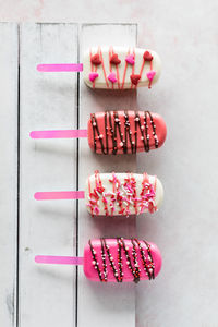 Vertical view of valentine cakesicles on a white rustic wooden board.