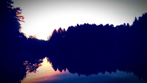 Reflection of trees in lake at sunset