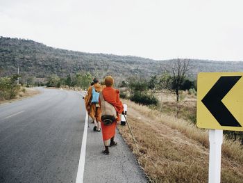 Rear view of man riding horse on road