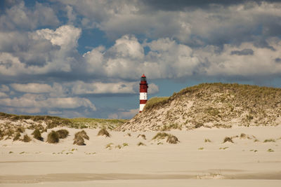 Lighthouse on beach against sky