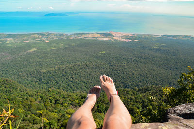 Low section of woman relaxing on rock at mountain