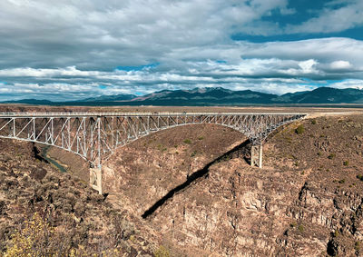 Scenic view of bridge over mountains against sky