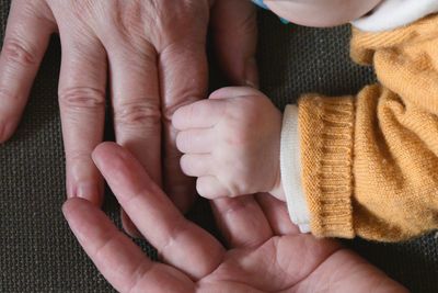 Cropped hands of parent and baby at home