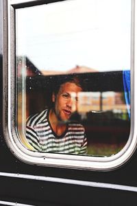 Man traveling in train seen through window
