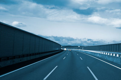 Road leading towards bridge against sky