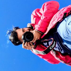 Low angle view of woman photographing against blue sky