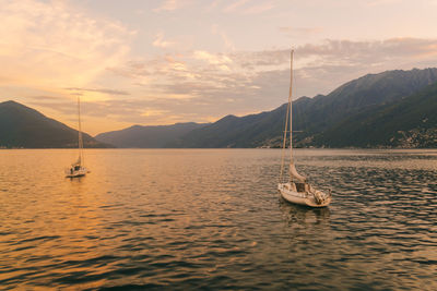 View of lake locarno at sunset with sailing boats and mountains