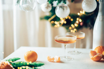 Champagne and tangerines in glasses on table