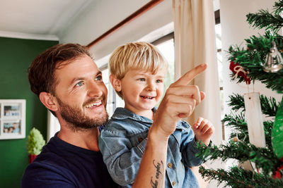 Father and son touching christmas tree at home