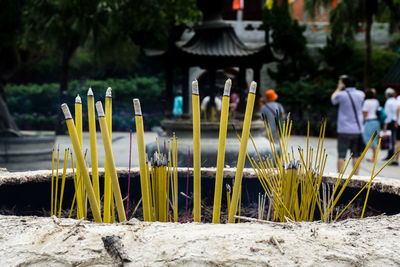 Close-up of incense sticks with people in background