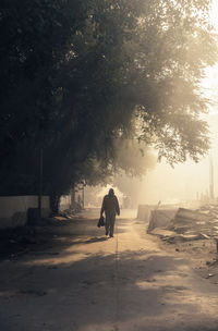Rear view of man walking on road against sky