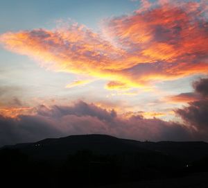 Scenic view of silhouette mountains against orange sky