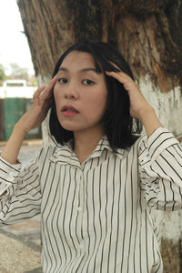 Portrait of woman against tree trunk