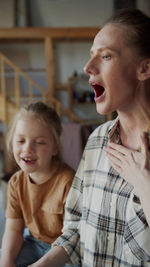 Happy mother and daughter playing with daughter at home