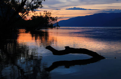 Sunset on the lake surrounded by mountains and trees in summer. reflections in water