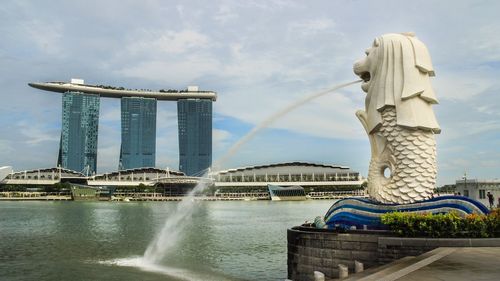 View of merlion statue and marina bay against sky