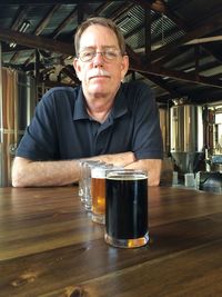 Portrait of man sitting with beer on table at brewery