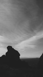 Silhouette rocks by sea against sky