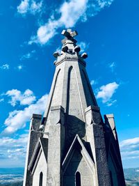 Low angle view of statue by building against sky