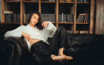 Side view of young woman sitting on bed at home