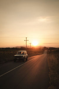 Cars on road against sky during sunset