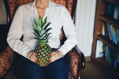 Midsection of woman holding pineapple at home