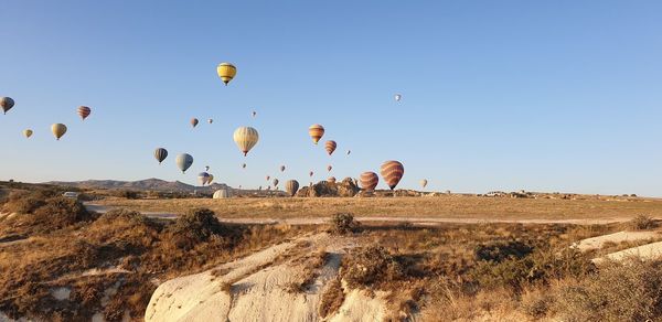 Hot air balloons flying over land against clear blue sky