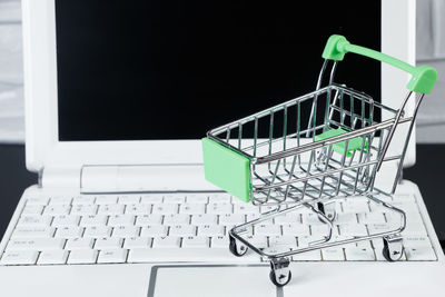 Close-up of miniature shopping cart on laptop