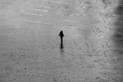 Rear view of child walking on frozen water 