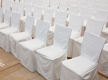 Empty white chairs arranged on tiled floor