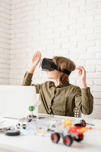 Nice teen boy in vr glasses sitting at the table playing game