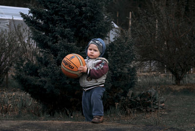 Portrait of boy holding ball in garden