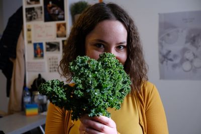 Portrait of young woman holding plants at home