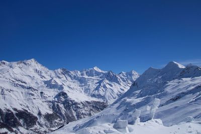 Scenic view of snowcapped mountains against clear blue sky