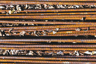 Old rusted iron bars and dry leaves on floor.  stack of straight old rusty steel reinforcement .