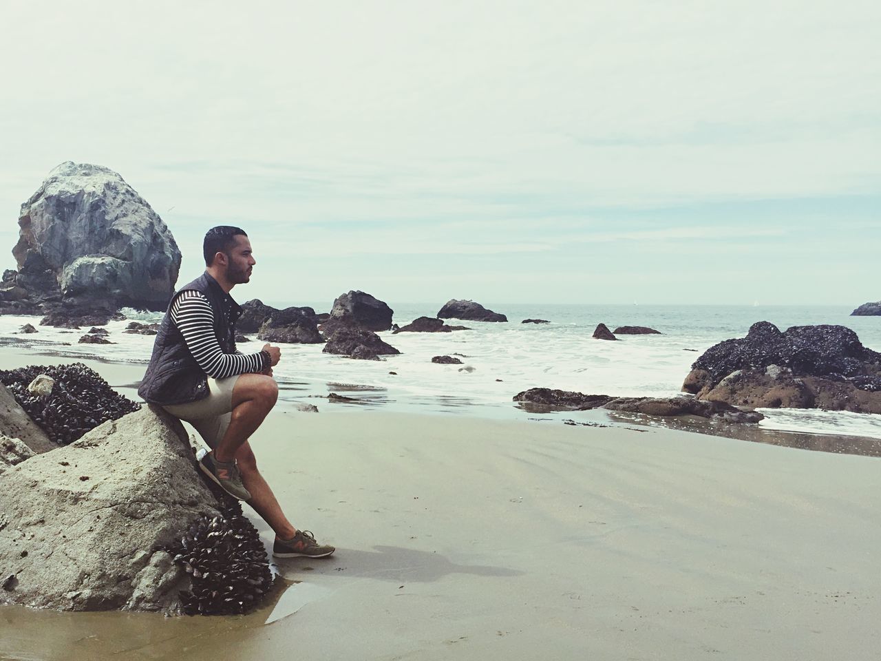 sea, beach, water, lifestyles, leisure activity, shore, horizon over water, full length, sky, vacations, young adult, sand, tranquility, scenics, tranquil scene, standing, casual clothing, rock - object