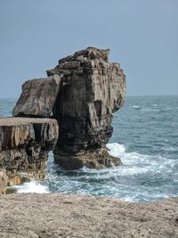 Rock formation on beach against clear sky