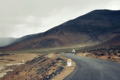 Road leading towards mountains against sky