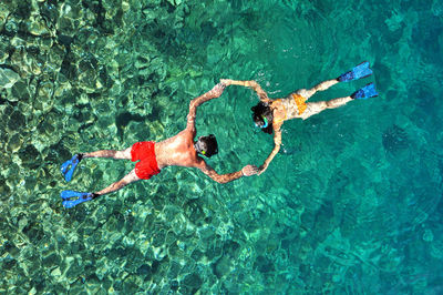 High angle view of man and woman snorkeling in sea