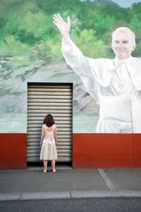 Rear view of a girl standing against the wall