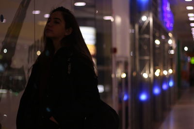 Portrait of woman standing in illuminated city at night